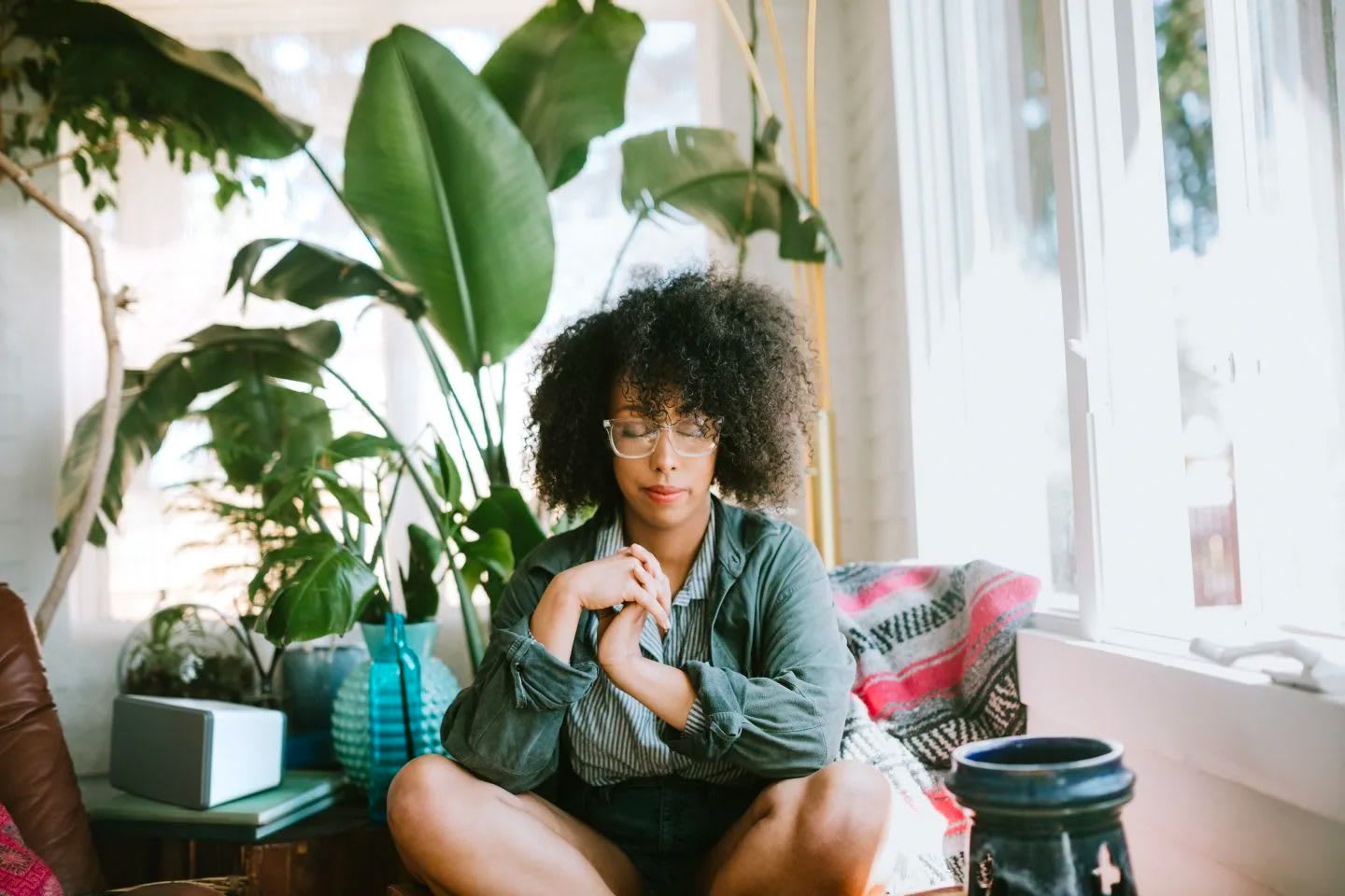Woman with afro sitting cross-legged with eyes closed daydreaming, calm, peaceful, mindfulness