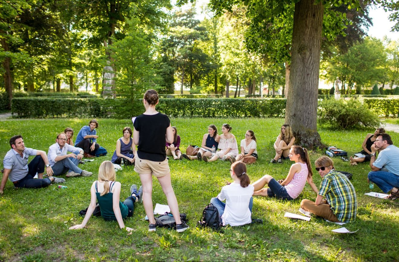 Students discussing and learning in a circle on the grass on a university campus, learning, outdoor, nature, workplace