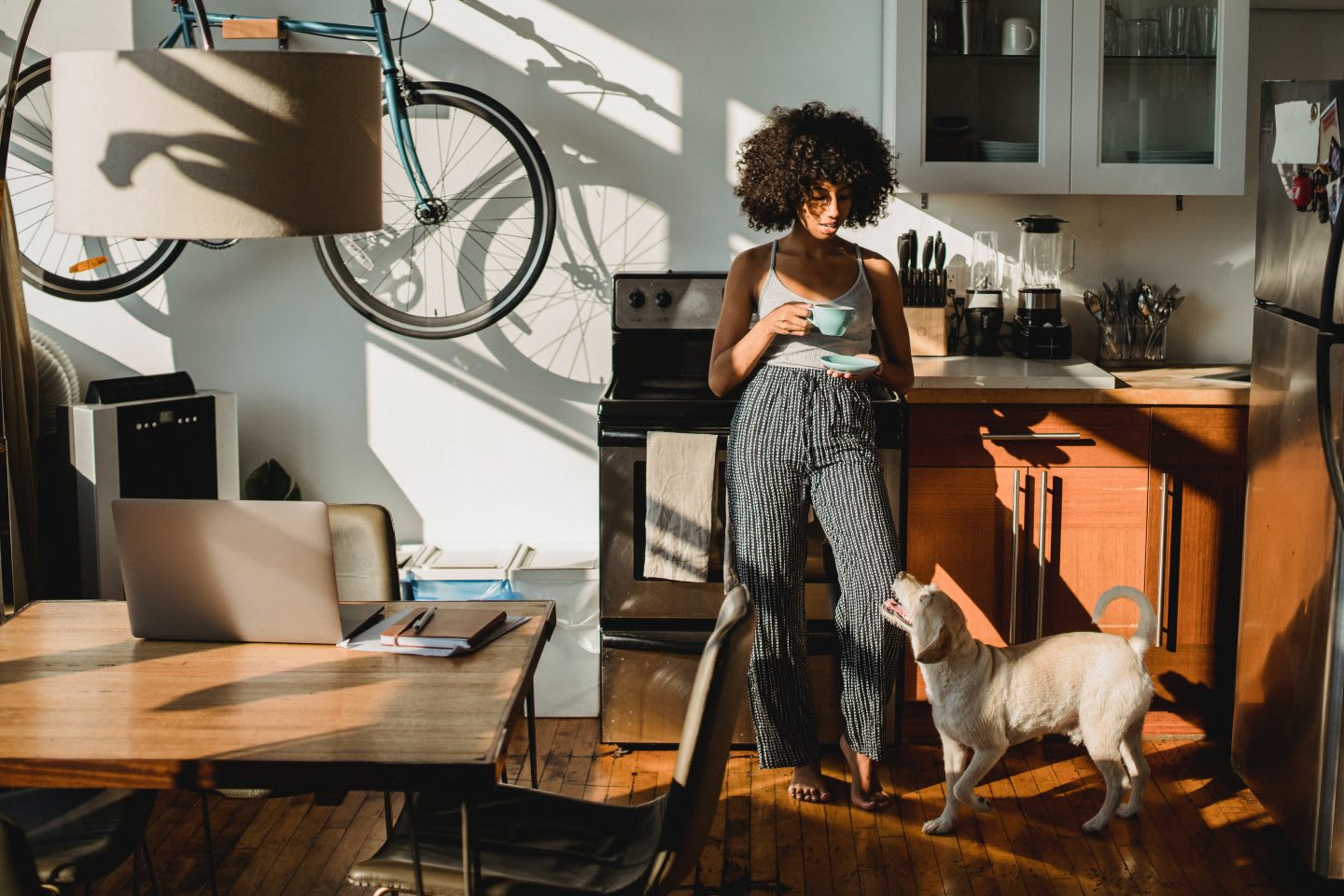 Woman standing in the kitchen with a coffee and a dog. Virtual meetings, home office, working from home,