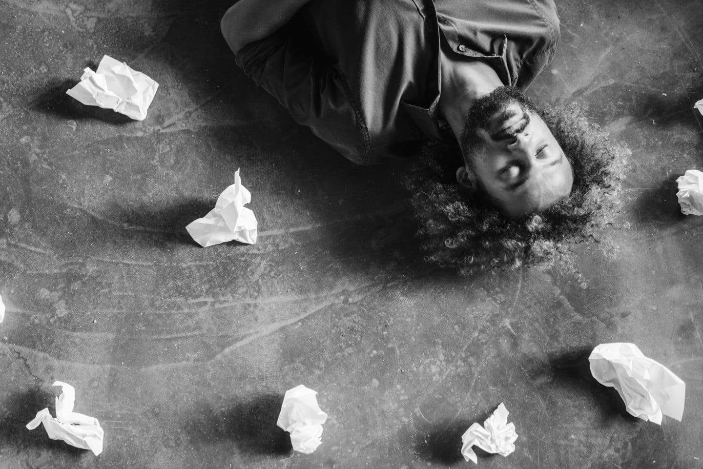 Man lying on floor surrounded by balls of paper, brainstorming, thinking, creative, ideas, GamePlan A