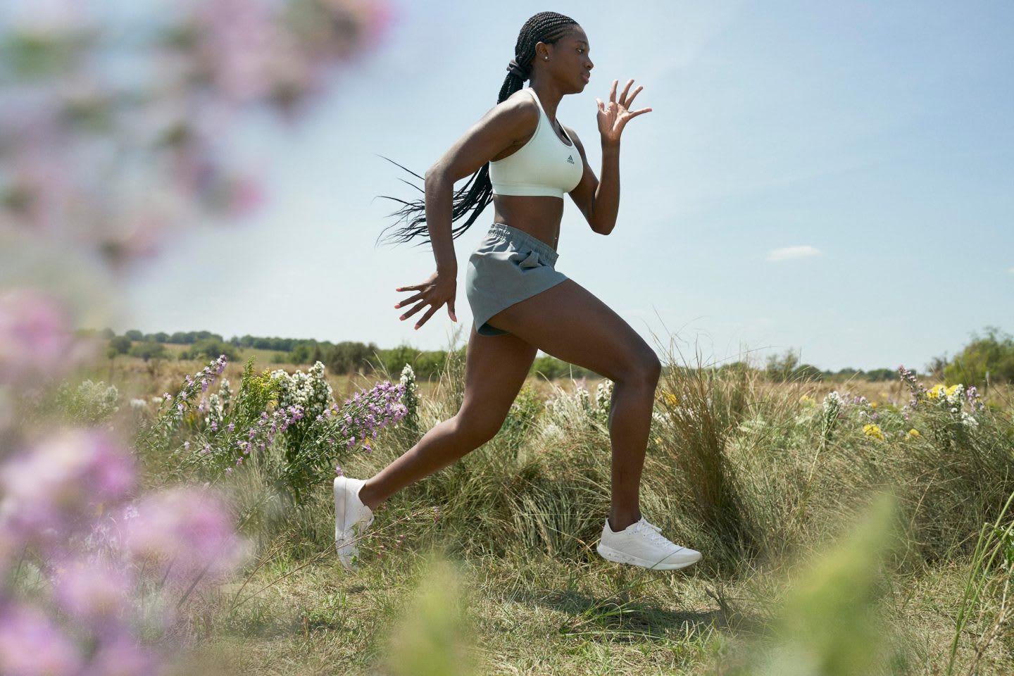 Woman wearing sports bra and shorts running in a field, adidas, FUTURECRAFT.FOOTPRINT, FUTURECRAFT, innovation, sustainability, carbon, adidas