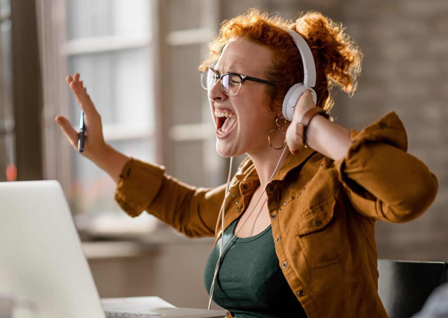 Woman wearing white headphones and singing while working on laptop, creativity, singing, sing, woman, voice