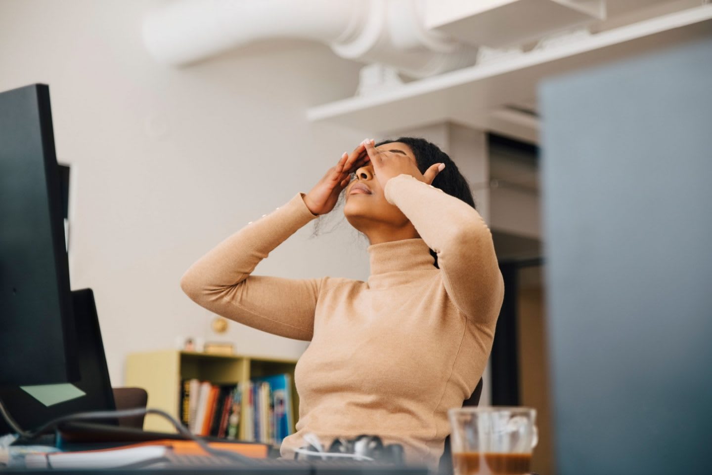 Woman wearing beige t-shirt hold face in hands in the office, stress, tiredness, exhaustion, office