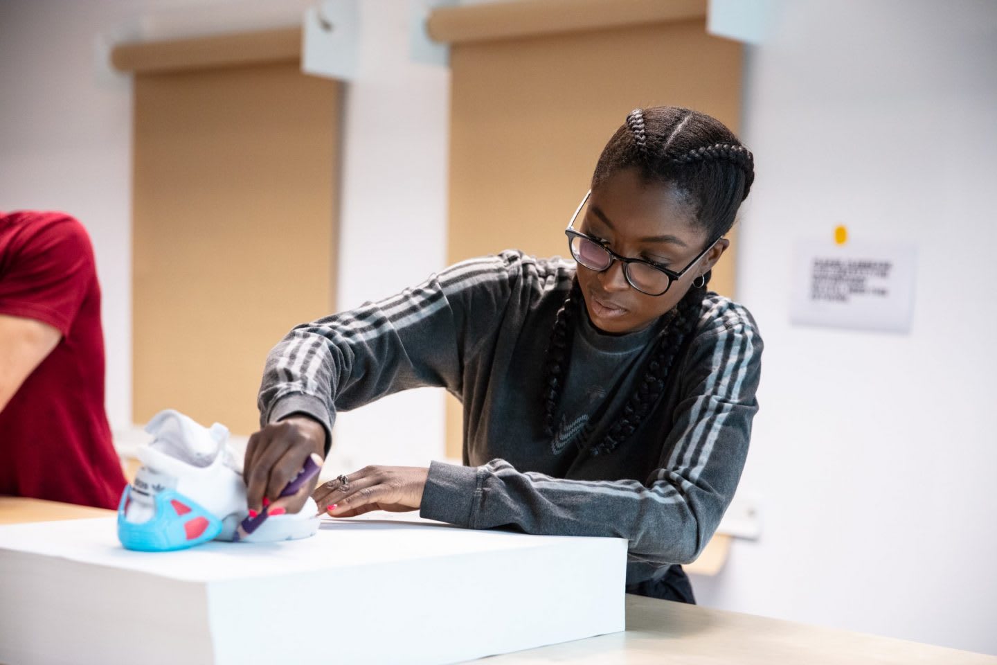 Girl wearing grey adidas sweatshirt and glasses working with shoes, adidas, employee, culture, workplace