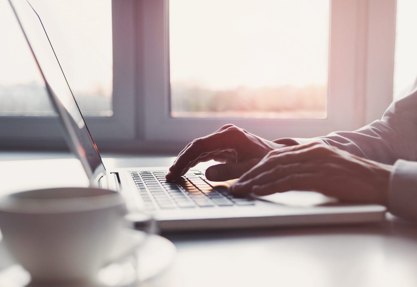 laptop-hands-sunrise-window-coffee