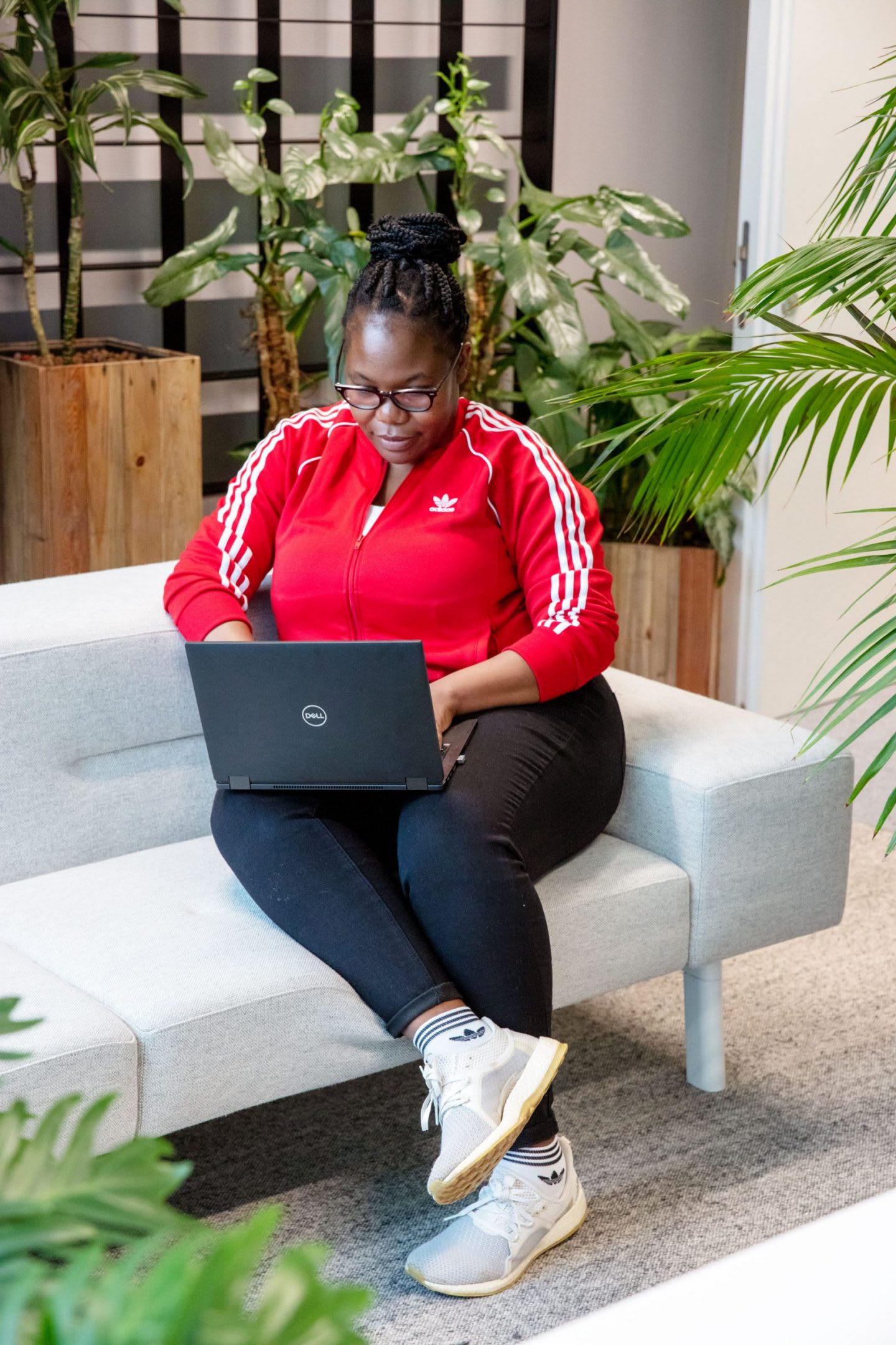 Blessing Malandu sits on a sofa working on her laptop.