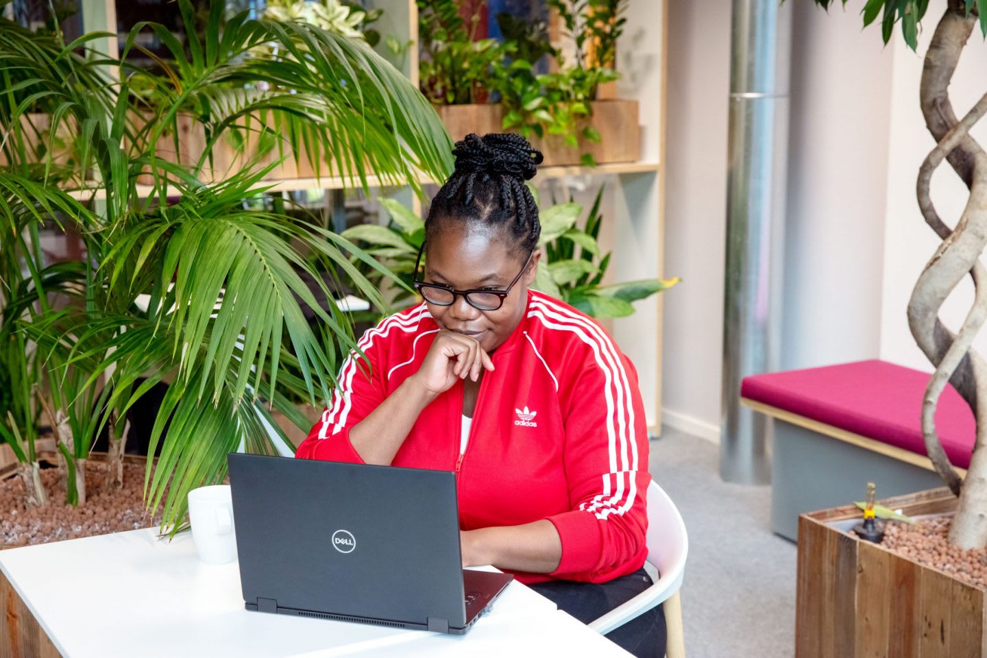 Blessing Malandu working on her laptop with plants in the background