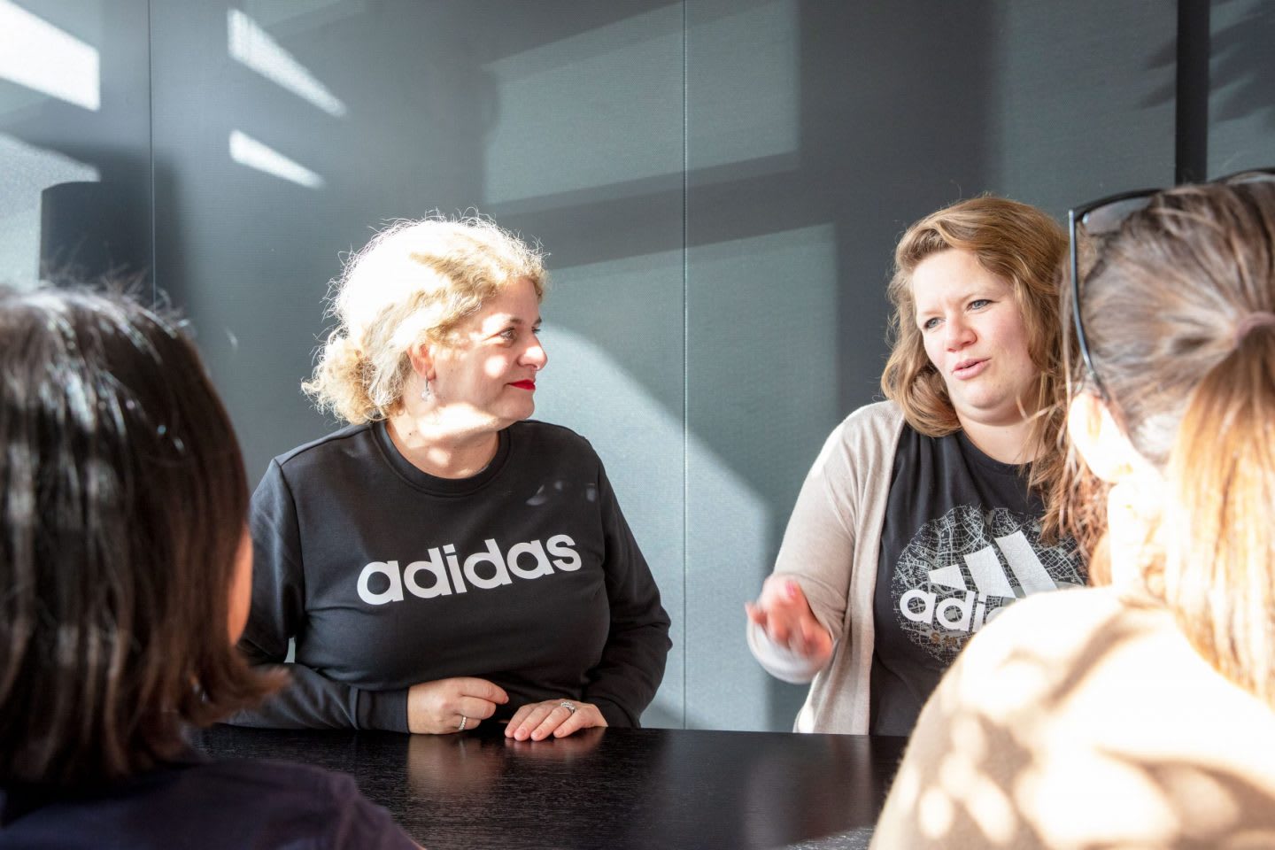 A group of people stand together engaged in conversation at adidas HQ.