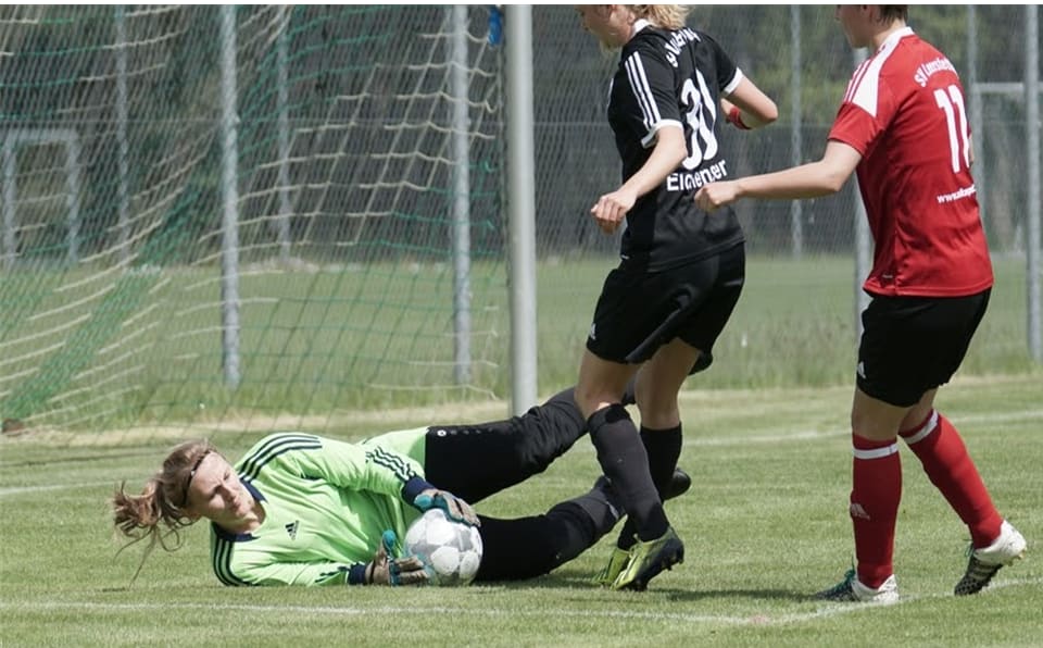 Goalie saves a shot from the attacking team during a football game.