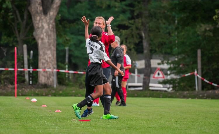 Football coach high fives her young player during a training session.