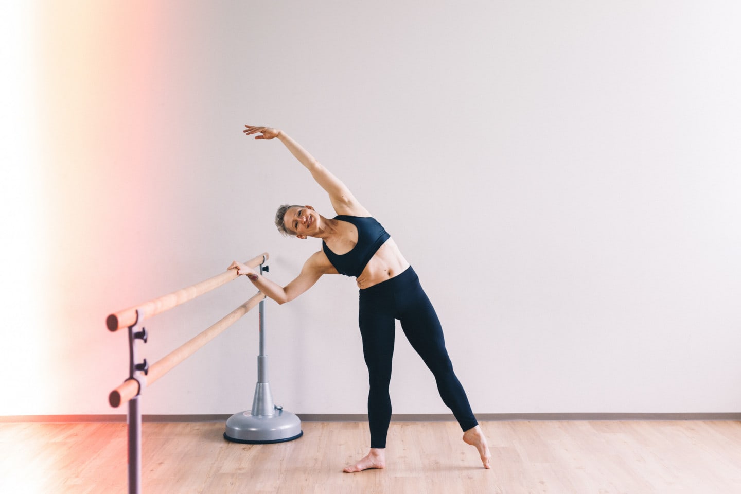 Woman performs barre class.