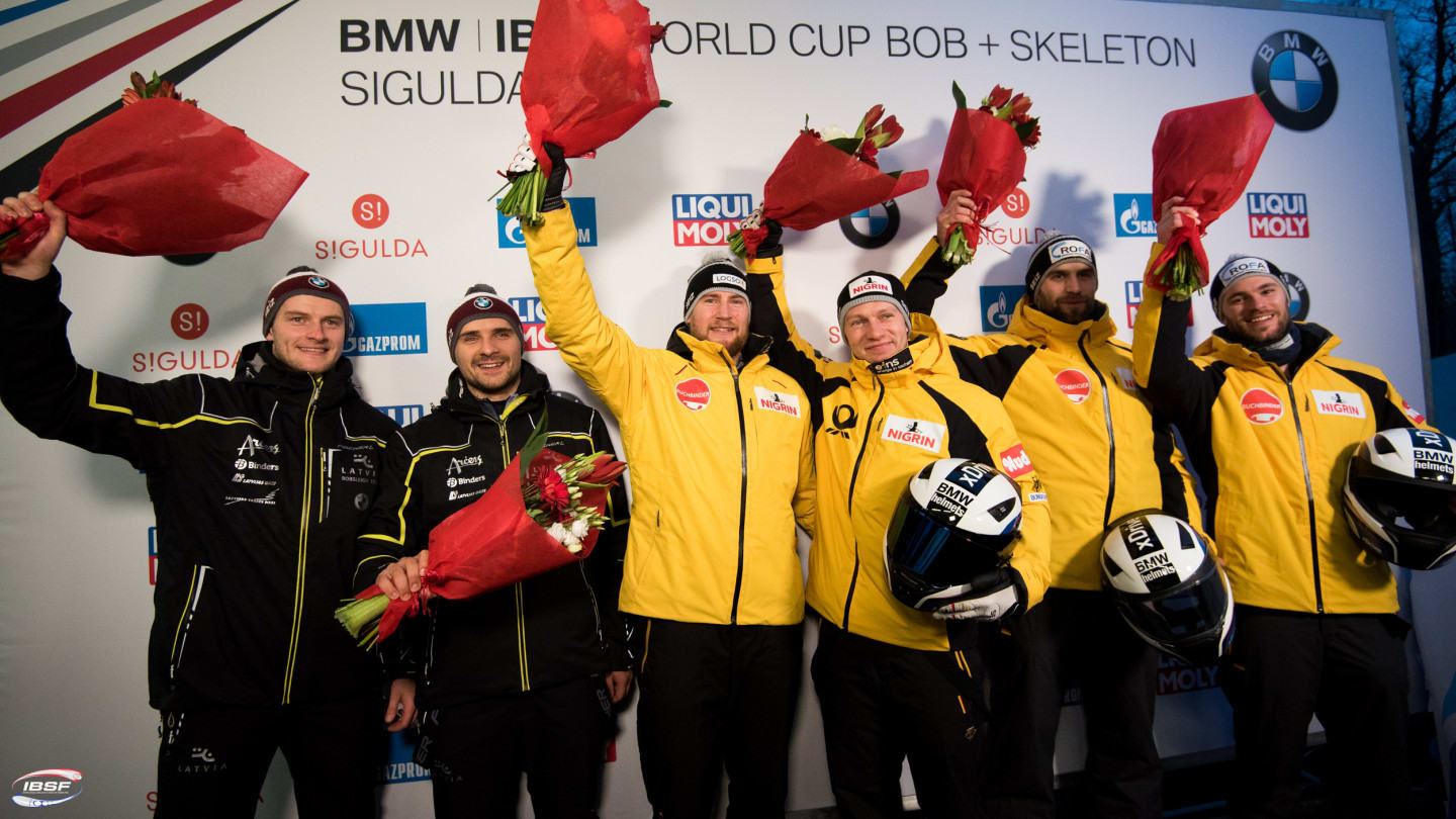 German Olympic bobsled team holding flowers in Beijing
