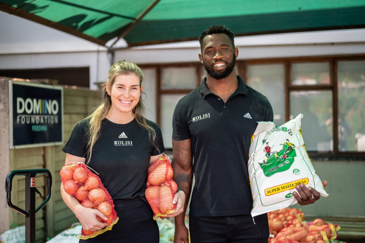 Siya Kolisi and his wife hold food supplies for their charitable foundation.