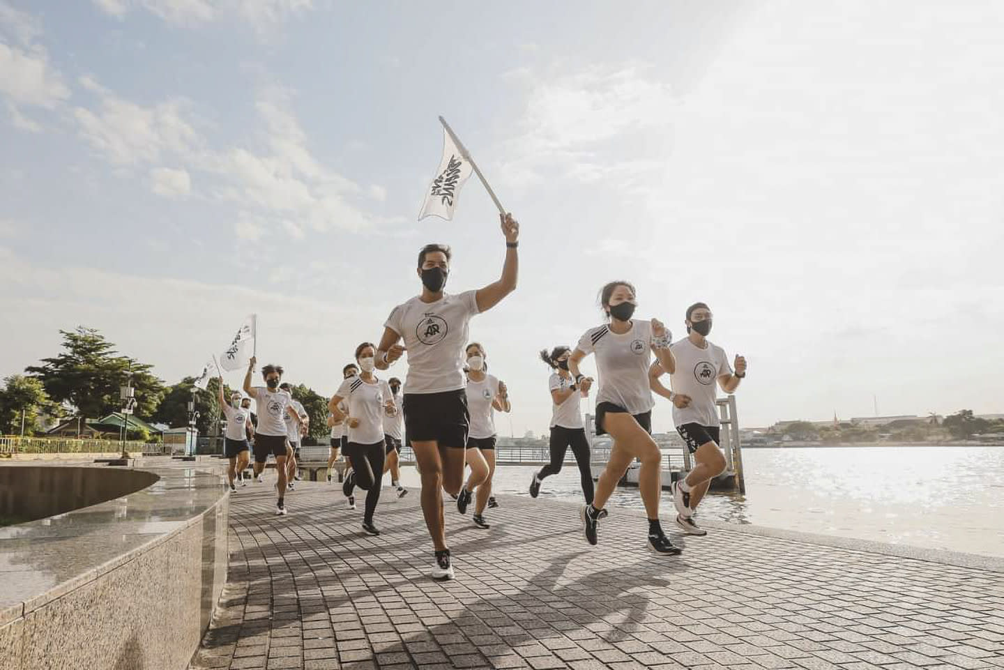 People in white t-shirts running together and waving flags