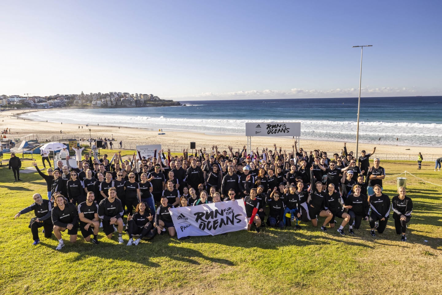 A group of people wearing black clothes posing with a flag in front of the ocean