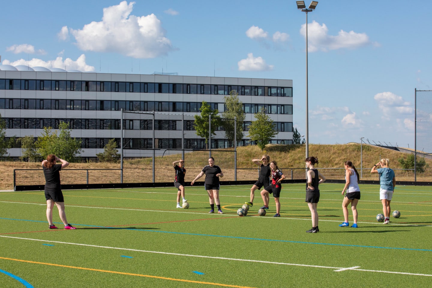 Women on a football pitch, preparing for a drill.