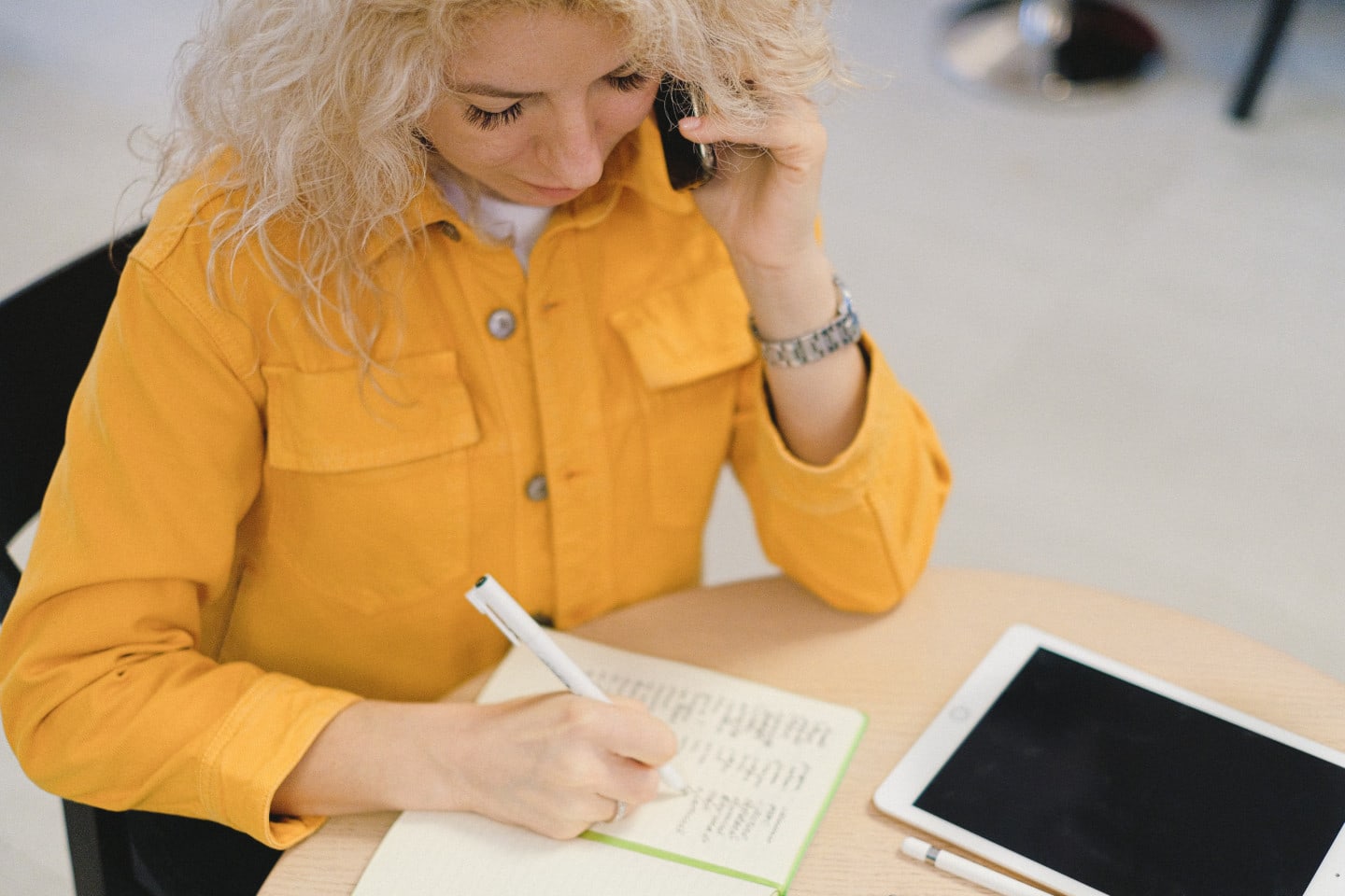 Stylish woman with white hair writes while on the phone