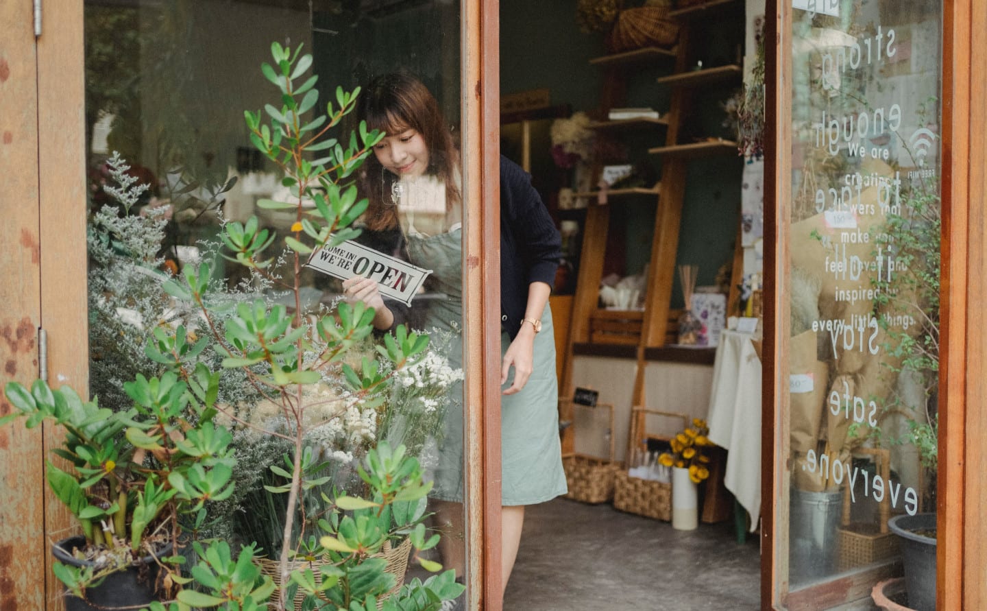 A woman puts out an open sign to her shop