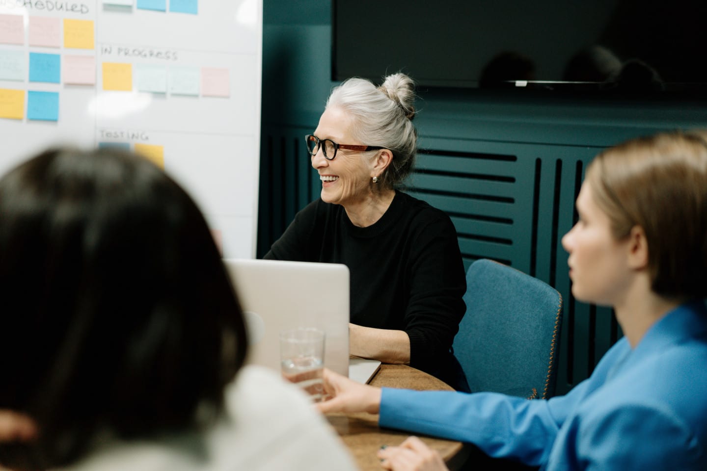 Woman with a gray hairbun with a laptop smiles