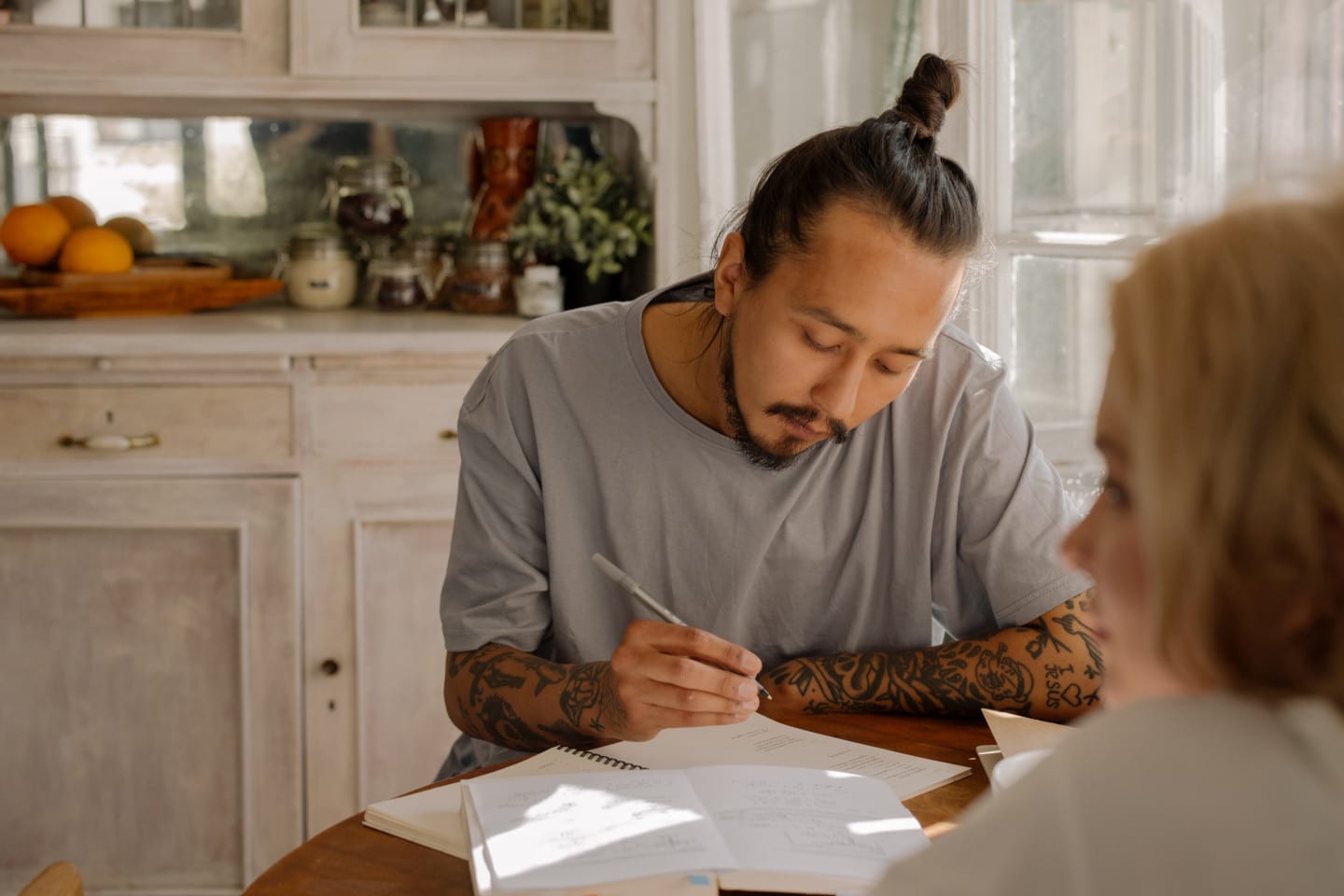 Man writing with a pen and paper at a table