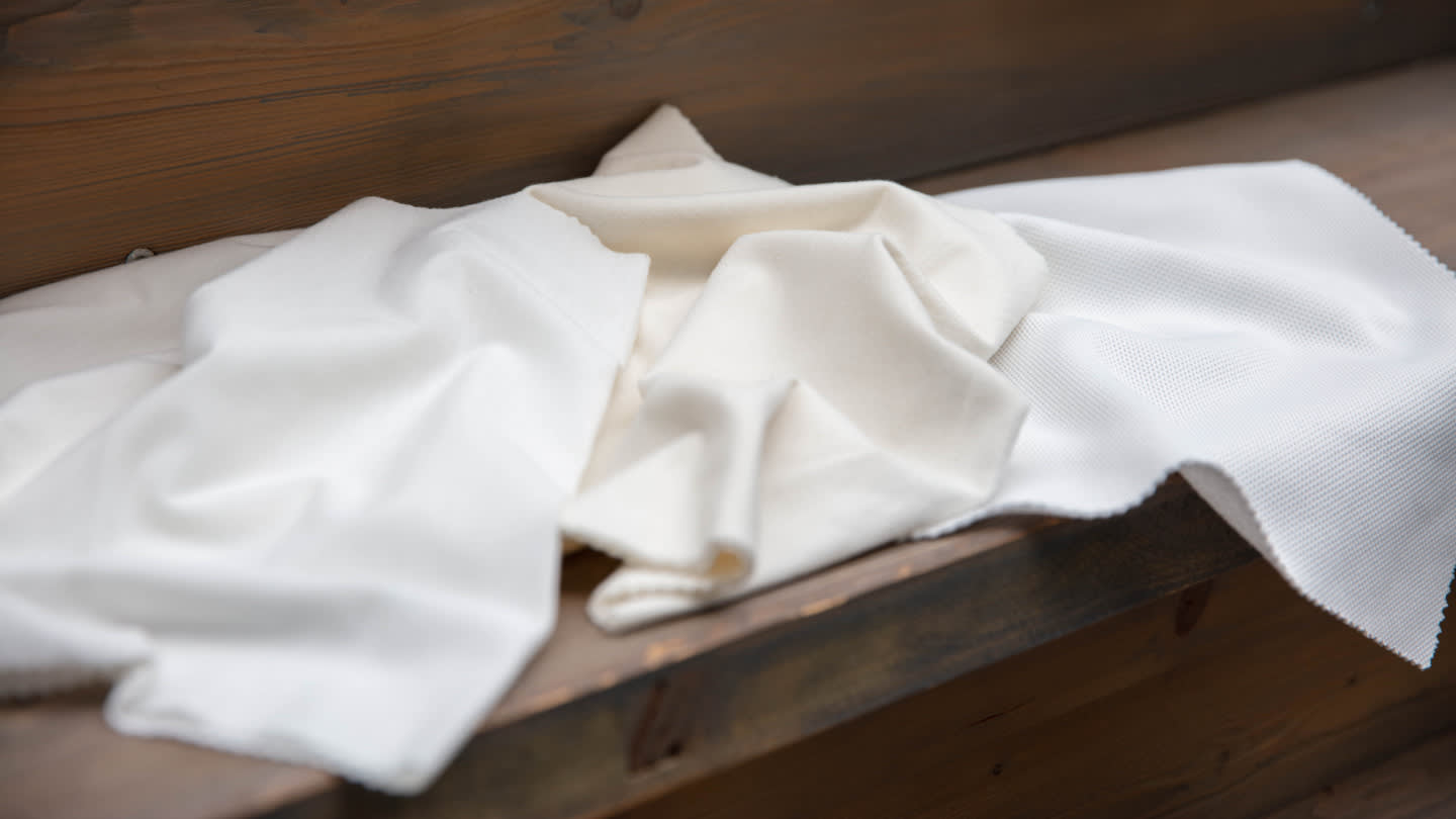 Pieces of undyed fabric resting on a wooden bench.