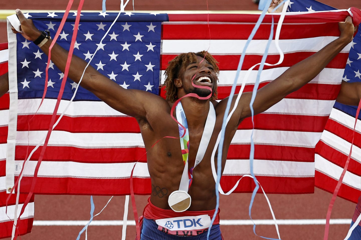 Noah Lyles holding an American flag behind his back at the World Championships