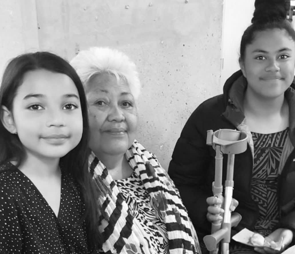 Two girls standing beside their mother smiling