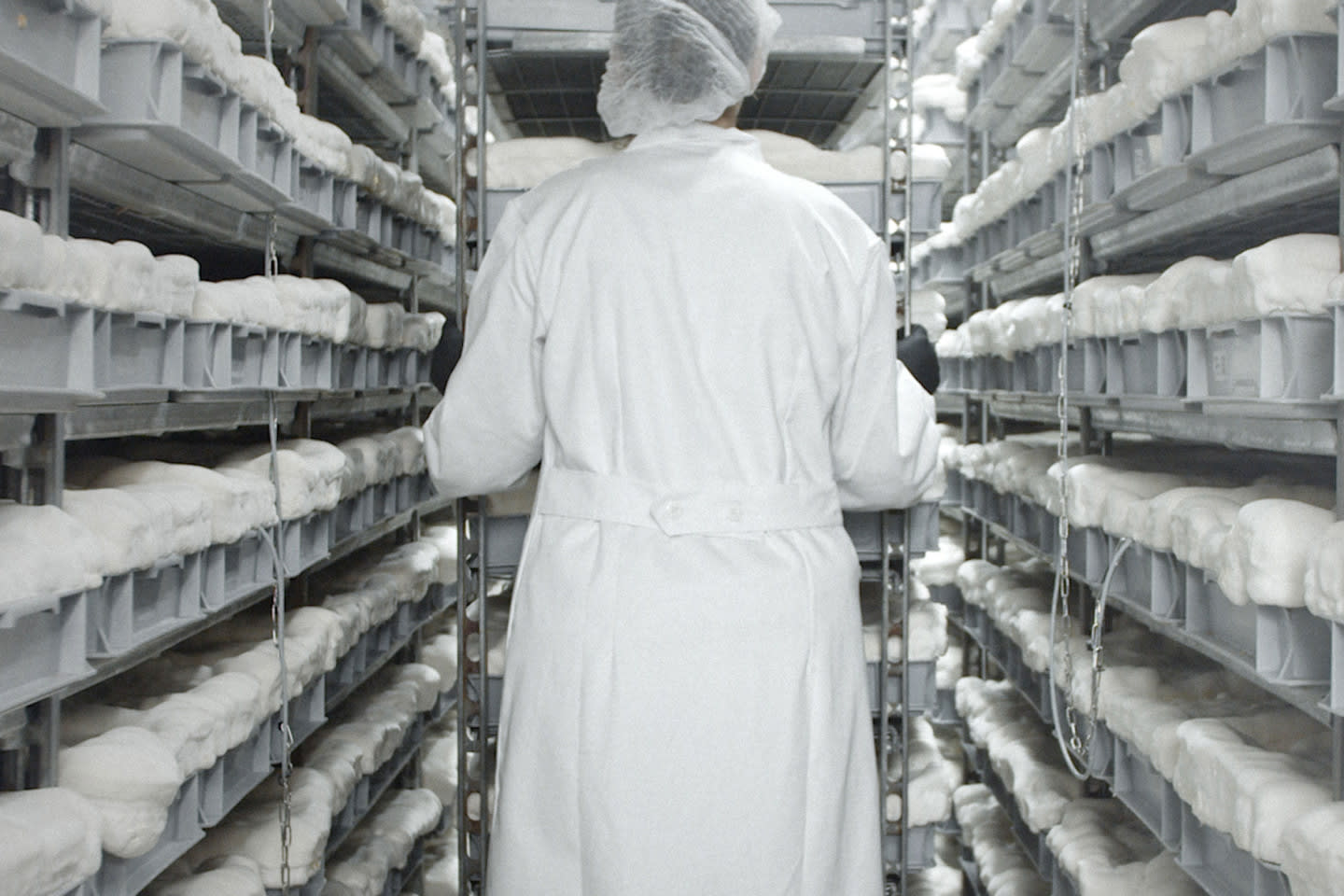 Person in lab coat walking through an isle with fabric on each side