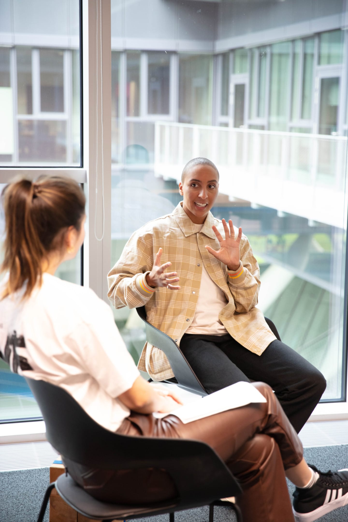 Two people sitting in chairs talking while wearing adidas
