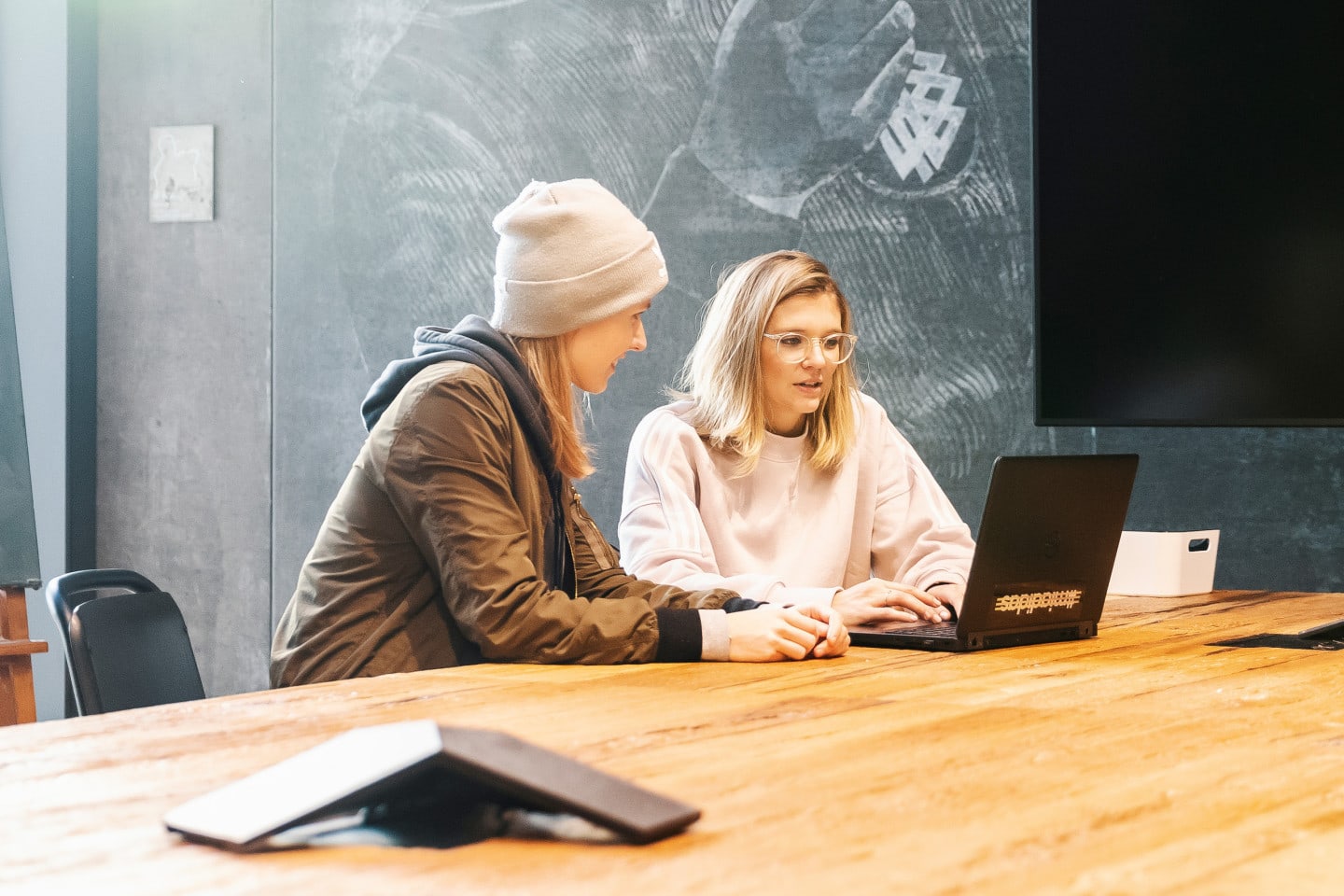 Two adidas employees working on a laptop together.