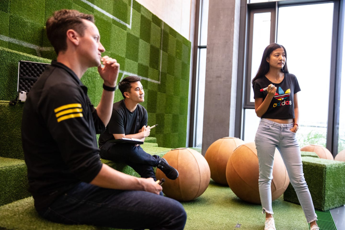 Three adidas employees in a green room working together.