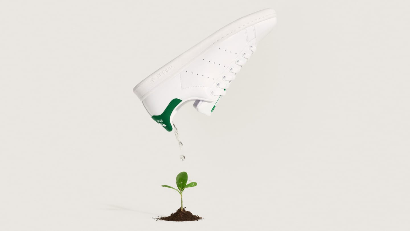 adidas sustainable Stan Smith mid-air above a plant.
