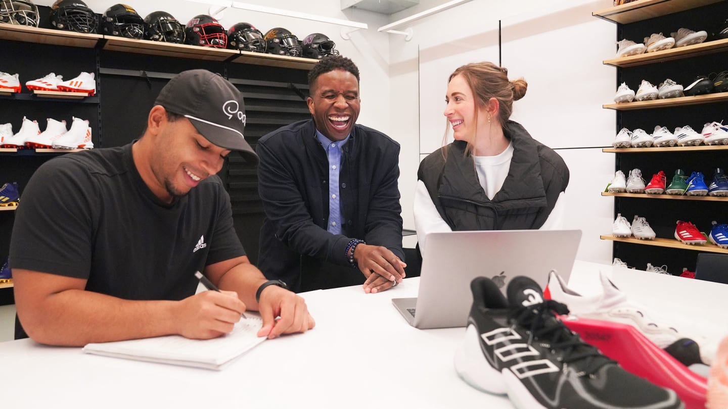 Three adidas employees laughing and working collaboratively together.