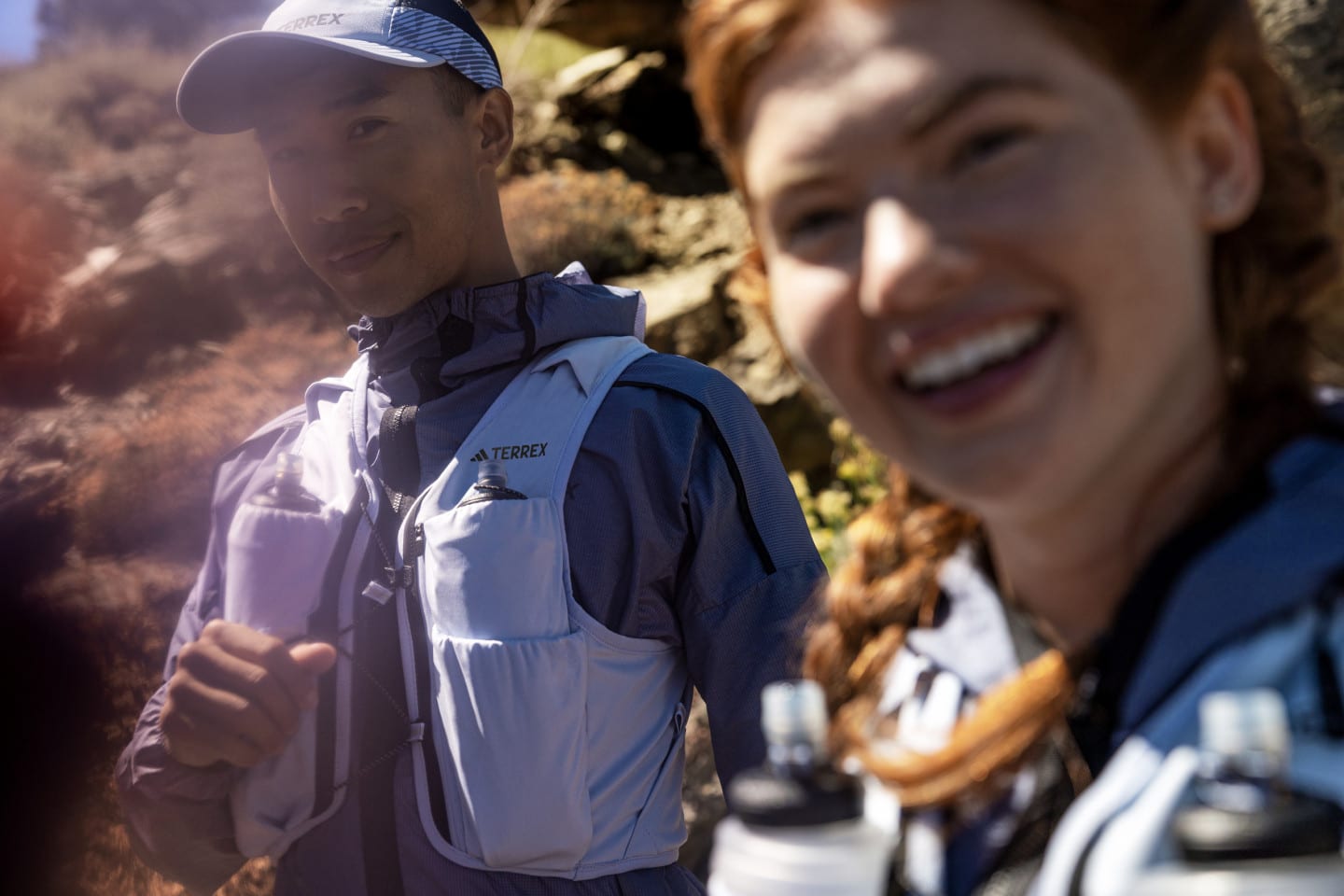 Two people smile and look at the camera while out on a trail run.