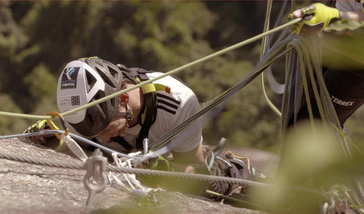 A man scales the side of a mountain with ropes alongside him.