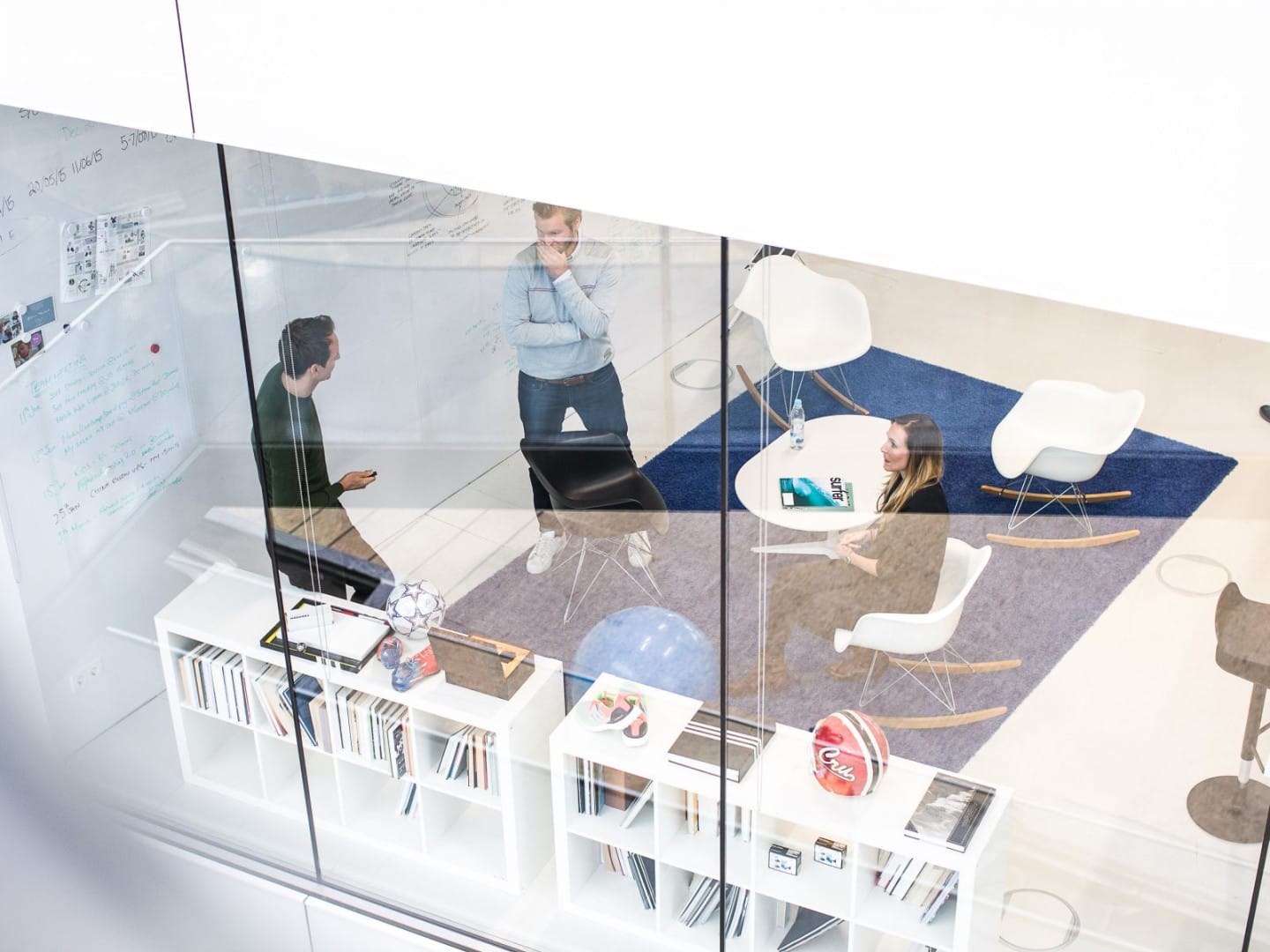 Birdseye view of a glass meeting room with people.