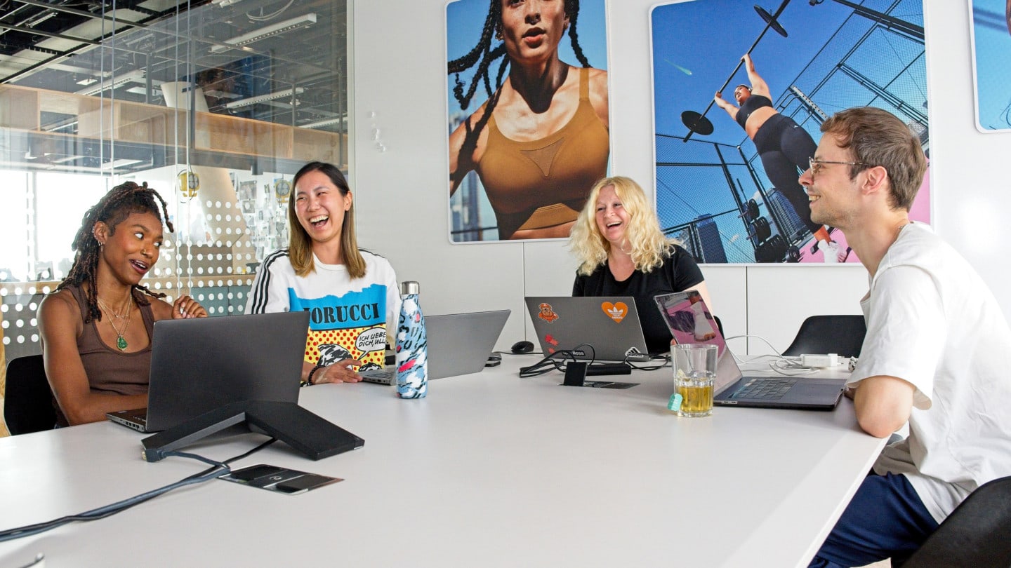 A group of people laugh as they sit around a conference room table.