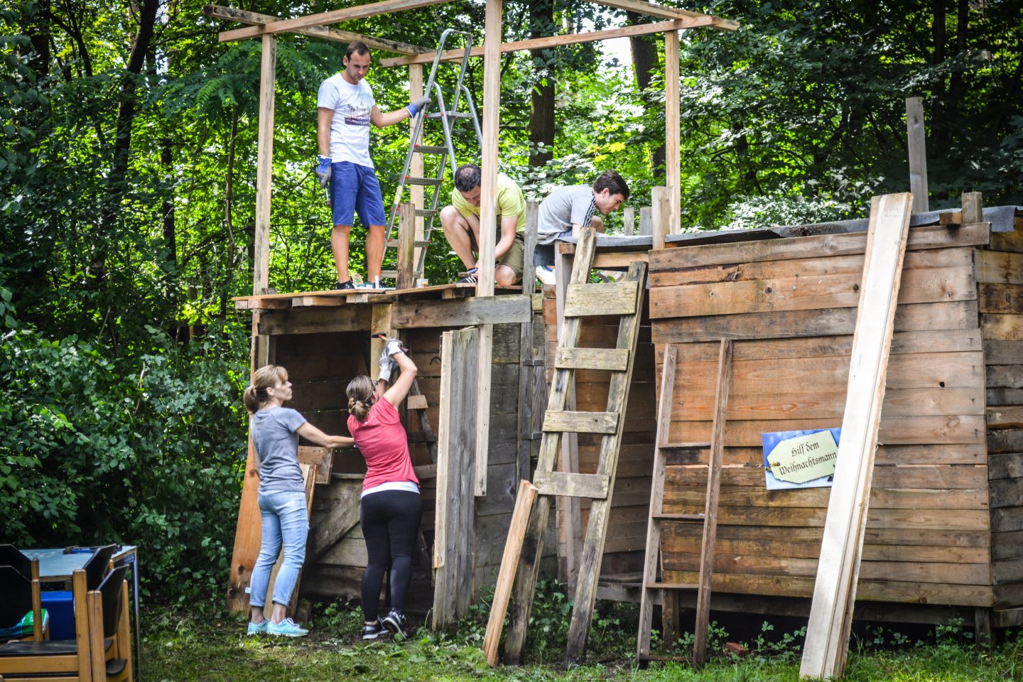 five people working on a treehouse