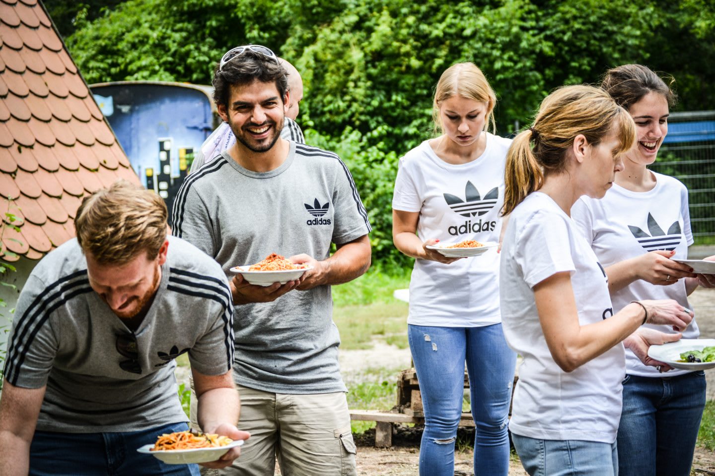 group of people in adidas shirts smile and eat lunch