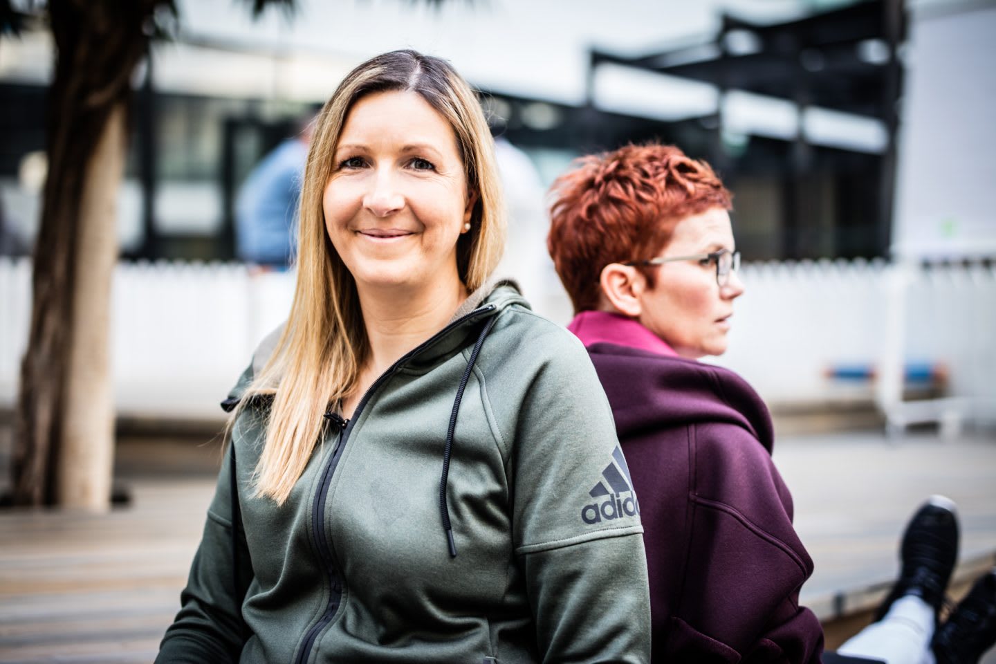 Blond woman with hoodie smiling job sharing at adidas