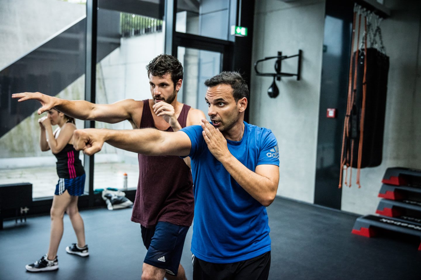 Boxing trainer giving advices to one of the participants by showing him how to box
