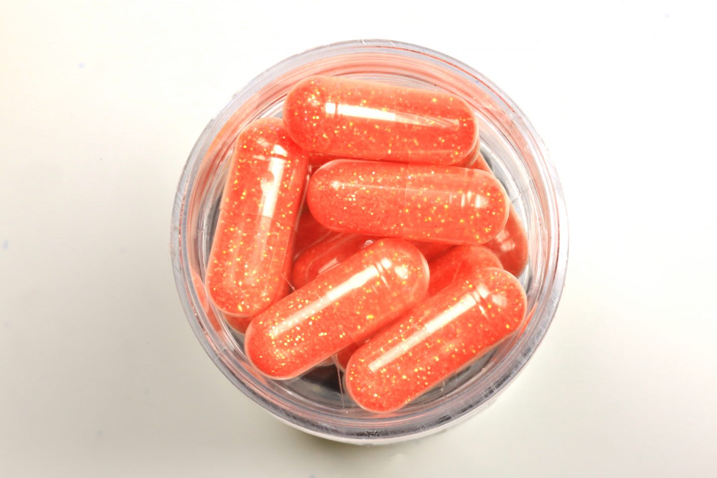 Overhead view of orange colored pills in a healthcare bottle, nutrition, health, diet