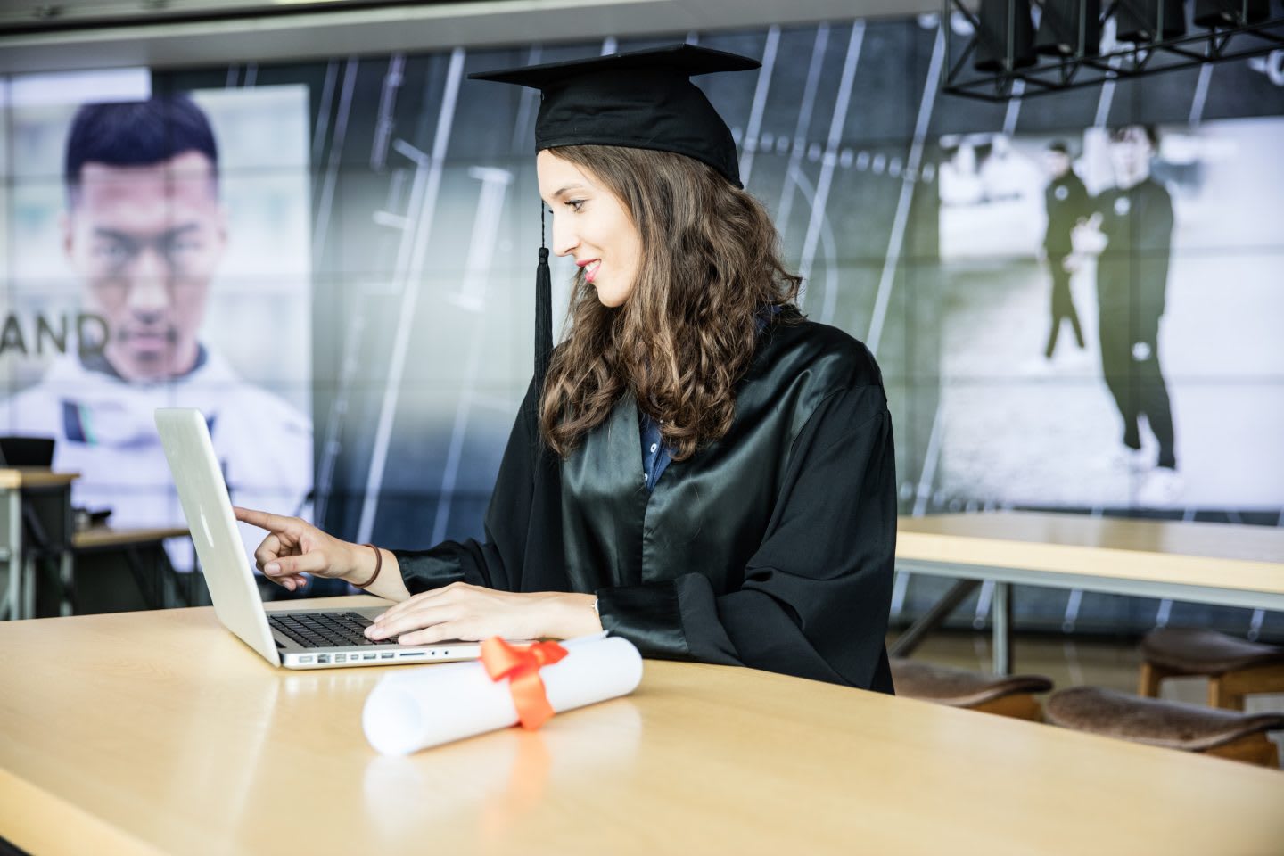 graduate works with laptop