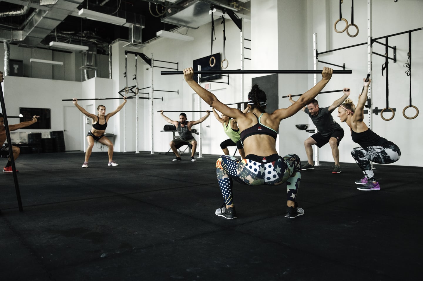 A group is working out lifting weights from a deep squat.