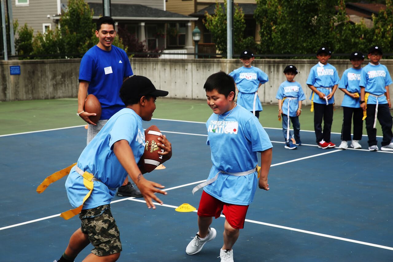 two kids are playing football outside