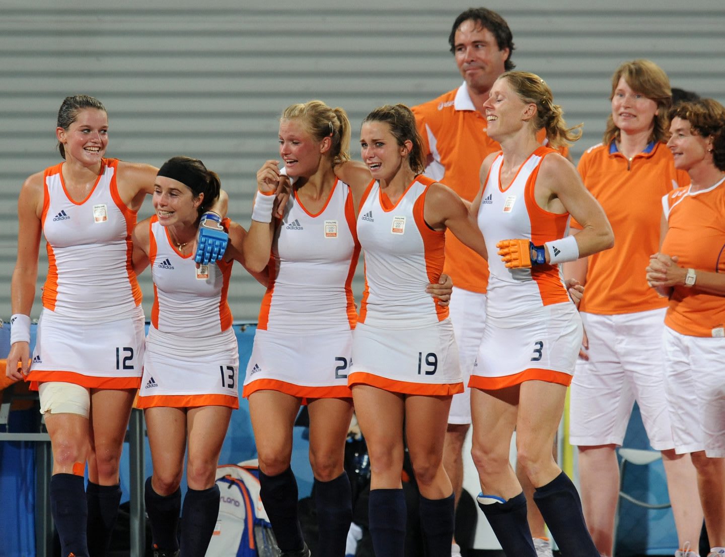 five teammates of the Dutch women's hockey team gathering after winning a match