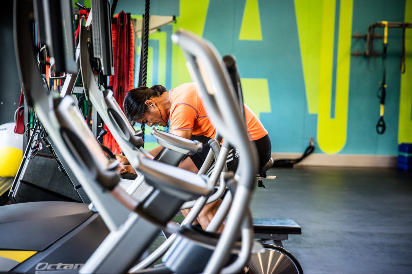 Guy in an orange shirt cycling in the gym.