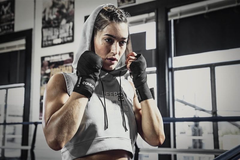 A female athlete wearing boxing bandages is arranging her hood while breathing deeply. Combat; adidas; Reebok; GamePlan A; Preparation; Success; Mindset; Energy; Workout