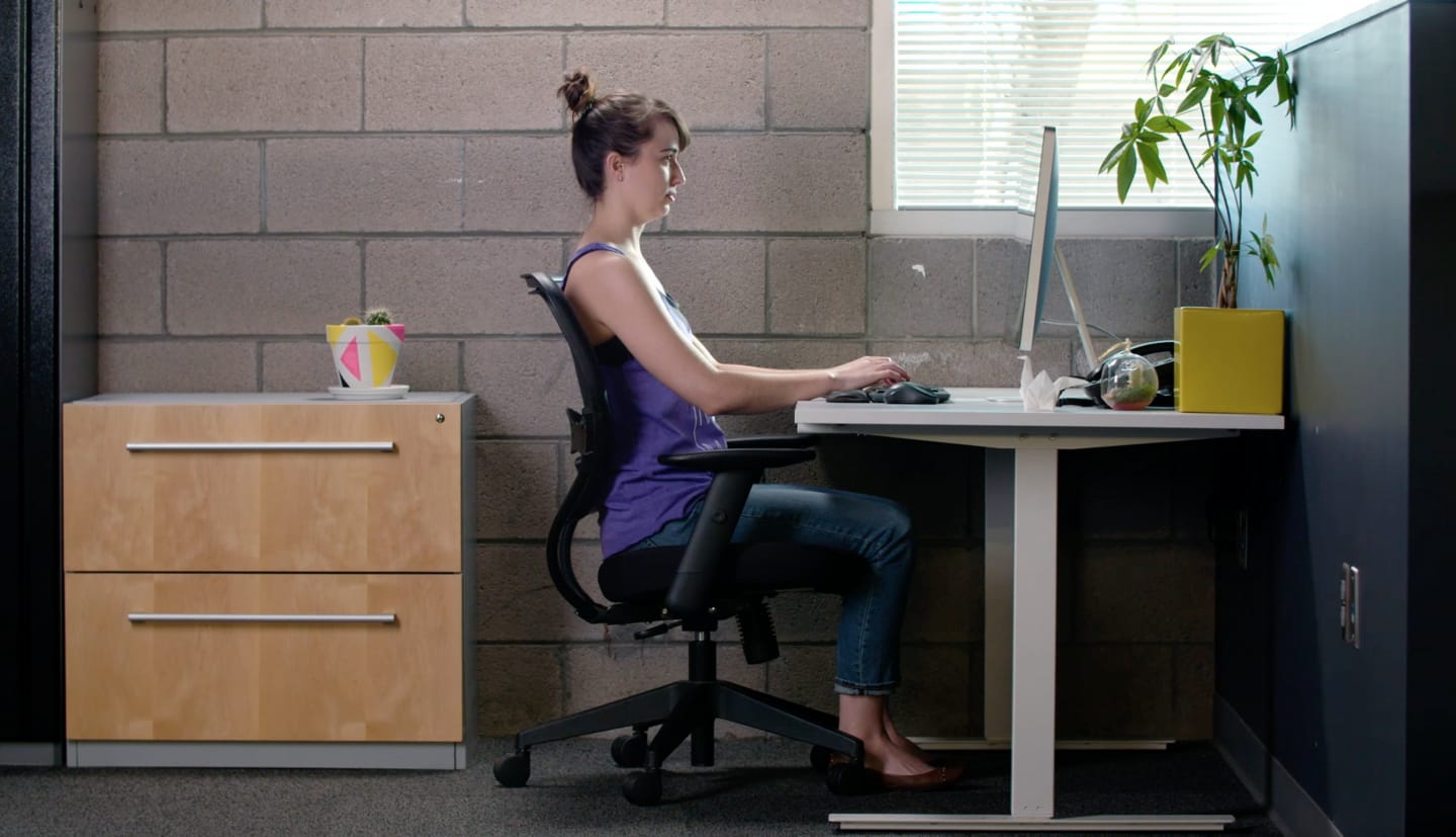 a woman sits at a desk typing on her computer. work, office, focus.