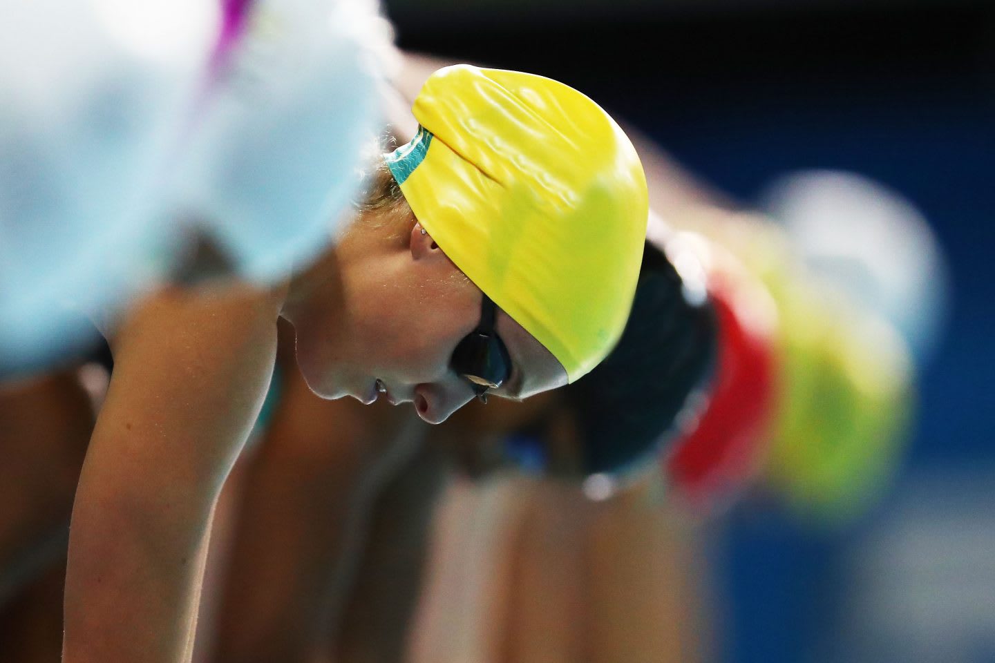 A line of swimmers take mark on the pool's edge in anticipation to dive into the pool. swimming, swimmer, competition, anticipation, focus